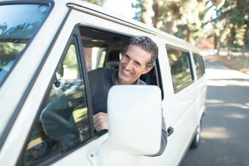 A picture of a happy person driving a larger vehicle in the neighborhood, covered by a vehicle protection plan.